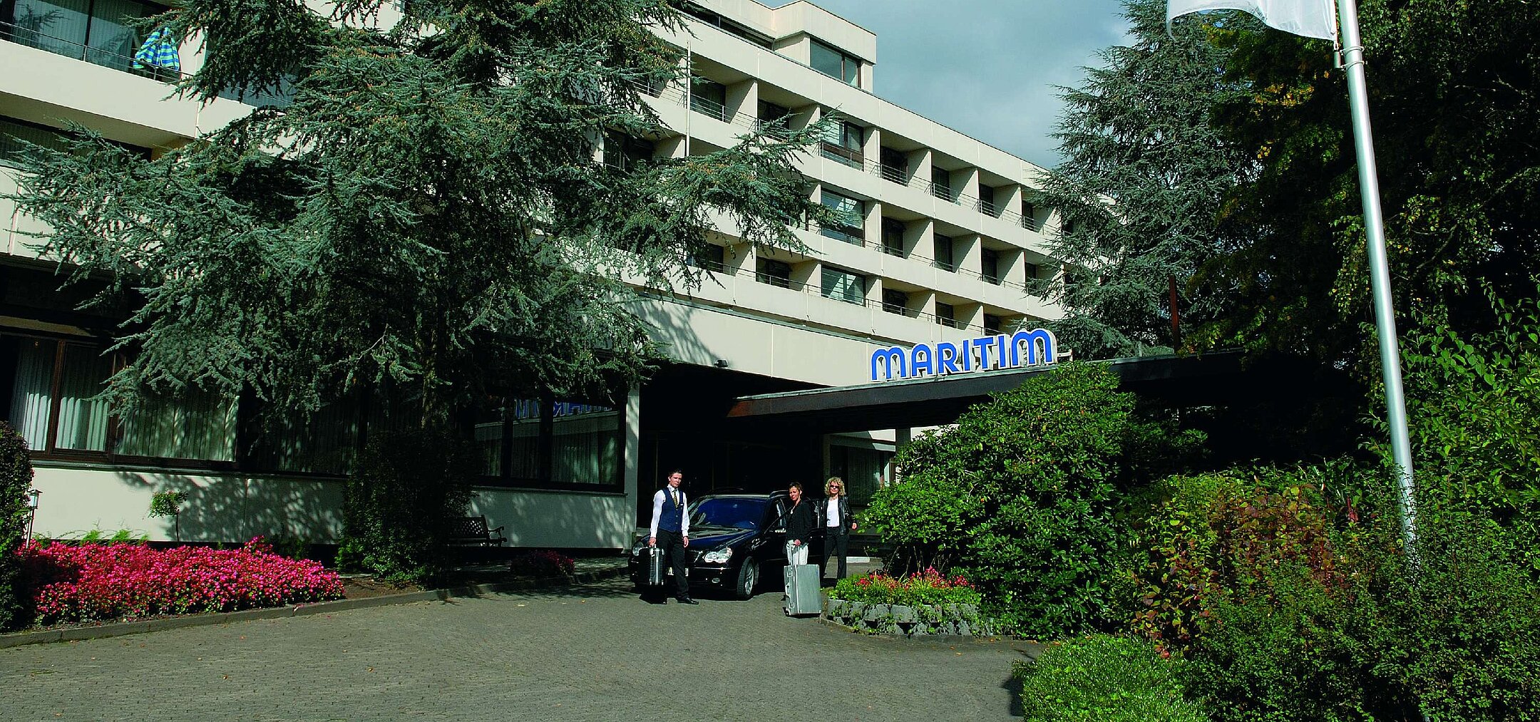 äste treffen am Eingang des Maritim Hotel Bad Salzuflen ein, umgeben von Bäumen und gepflegtem Grün