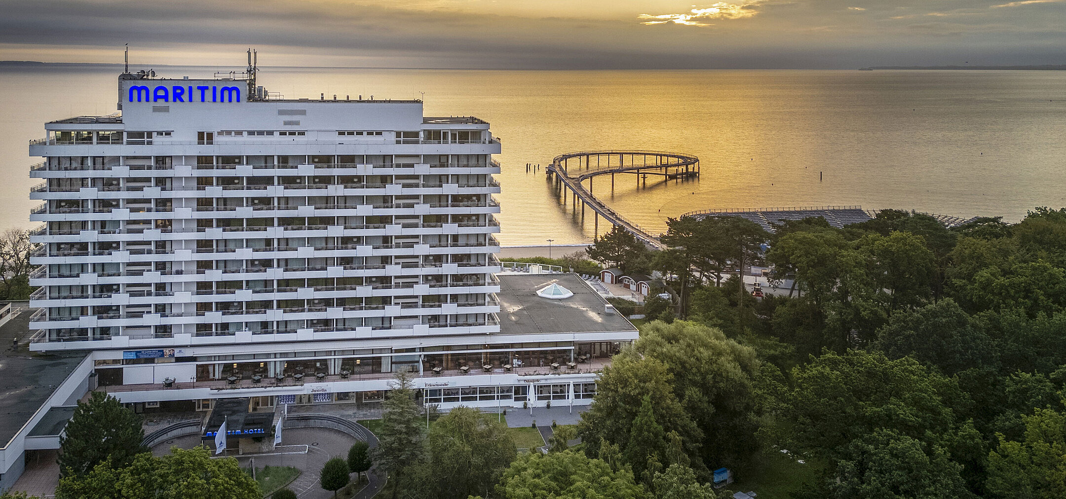 Maritim Seehotel Timmendorfer Strand bei Sonnenaufgang mit Seebrücke und Meerblick.