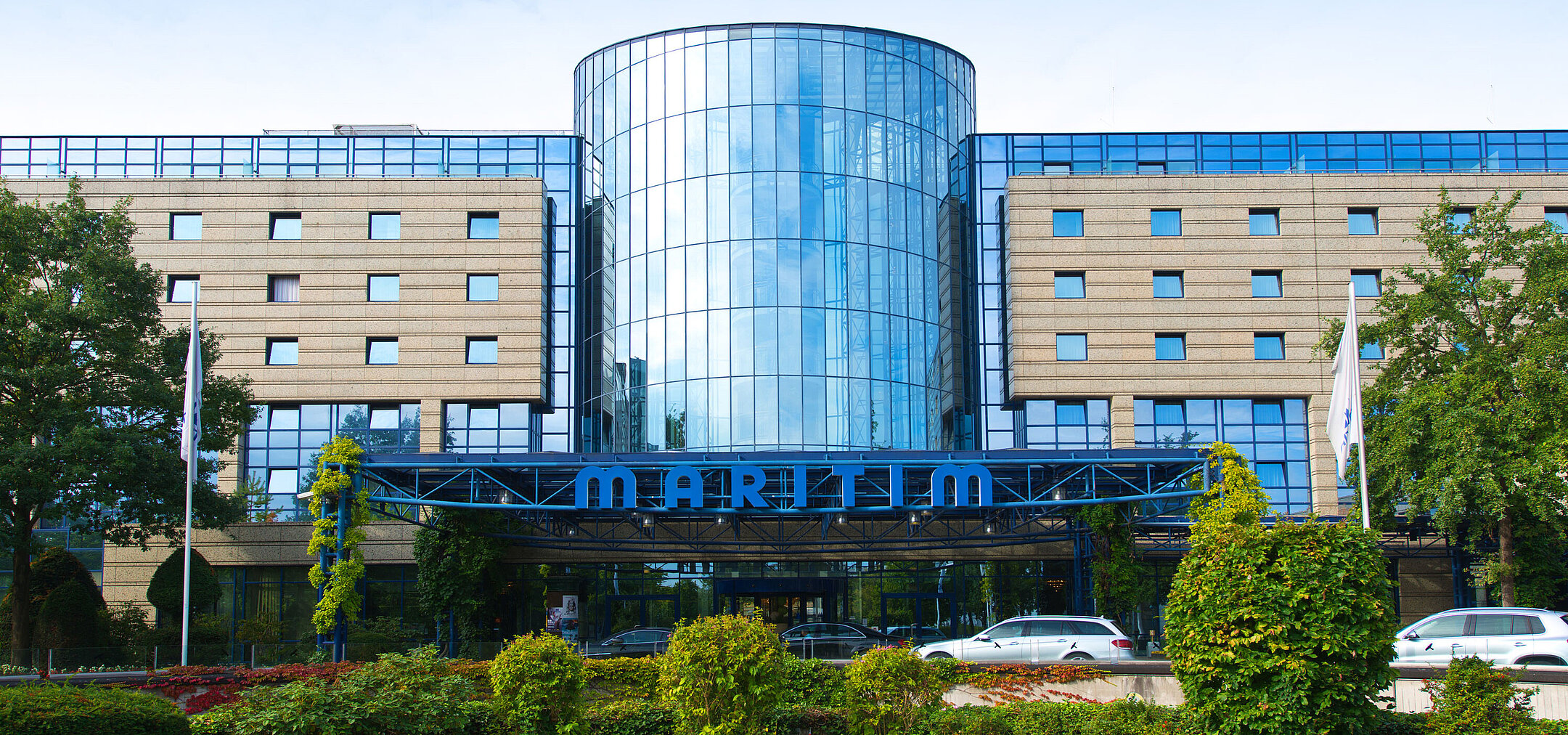 Außenansicht des Maritim Hotels Bonn mit moderner Glasfassade und gepflegter Gartenanlage im Vordergrund.