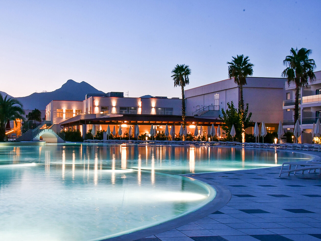 Poolbeleuchtung am Abend im Maritim Resort Calabria mit Palmen und Gebirgskulisse